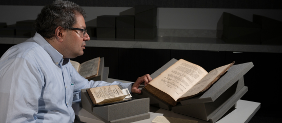 Adam Shear looking at open Hebrew books 