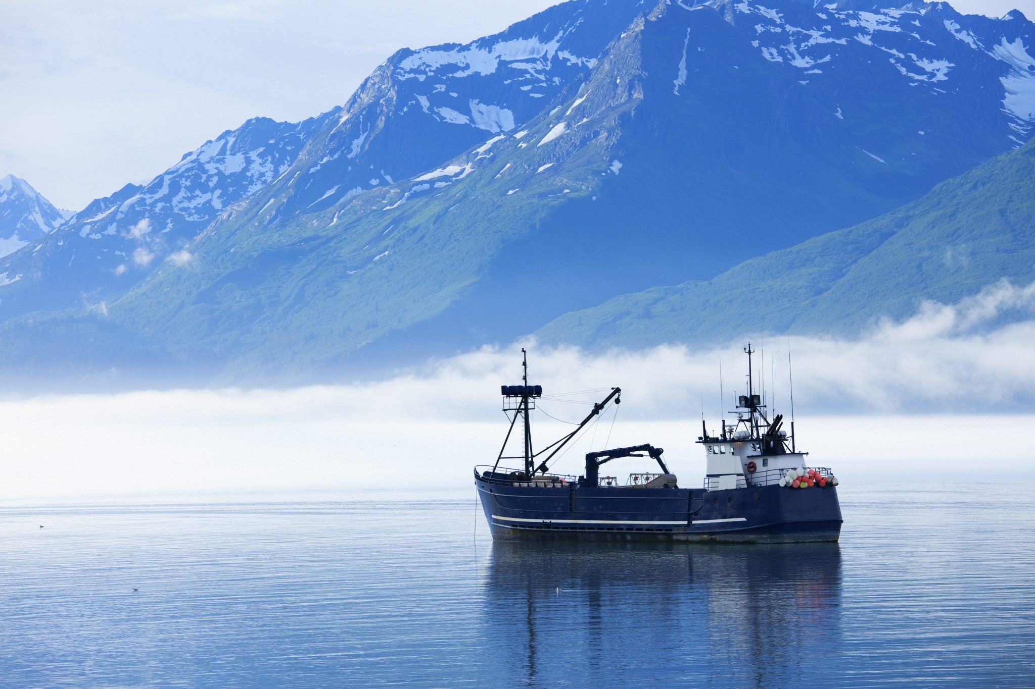 fishing boat on the water with mountains in the background.