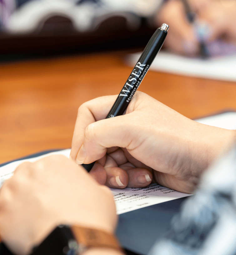hand holding a pen while writing on paper
