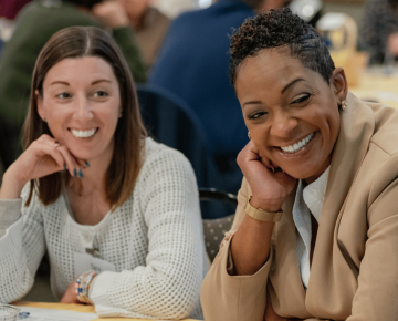 two women looking off screen at something while smiling