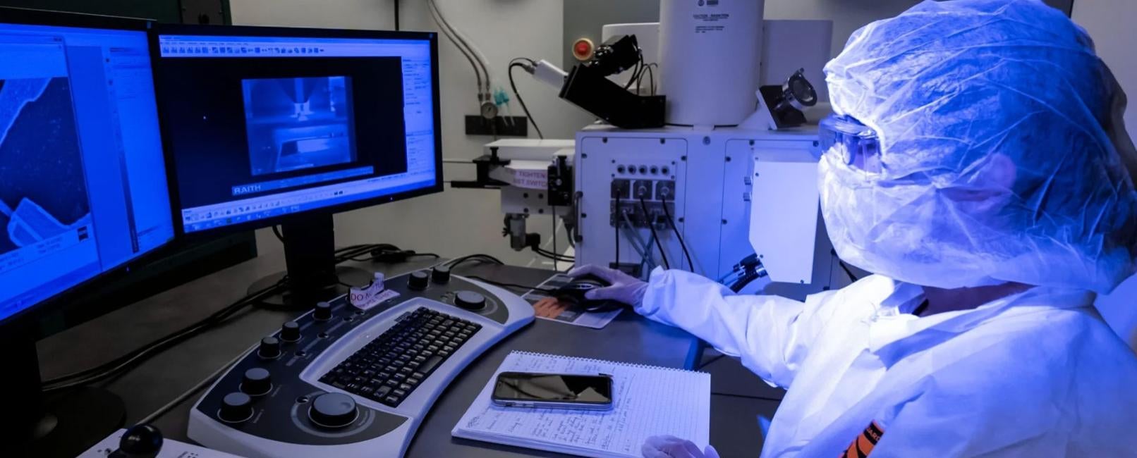 Person wearing lab coverings working on computer