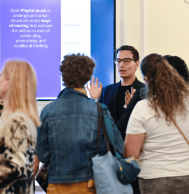 Group of people listening to a Pitt researcher present at the 2024 Pitt Research Internal Funding Showcase