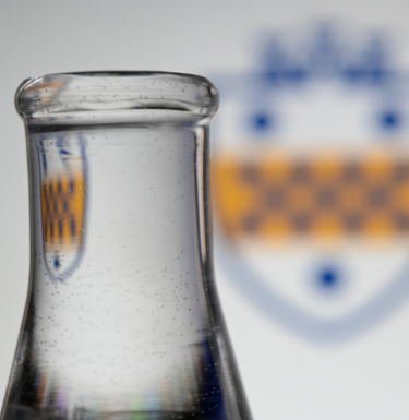 beaker in front of Pitt logo